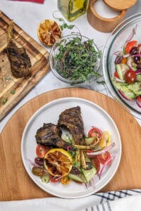 grilled lamb coated in zhug and ras el hanout easoning on tomato and cucumber salad and grilled lemon.